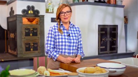 Borbás Marcsi mosolyogva főz a konyhában, körülötte friss alapanyagok