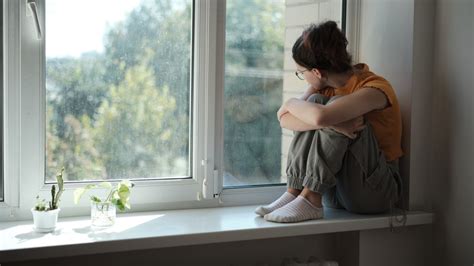 Egy magányos ember, aki egy ablakon néz kifelé