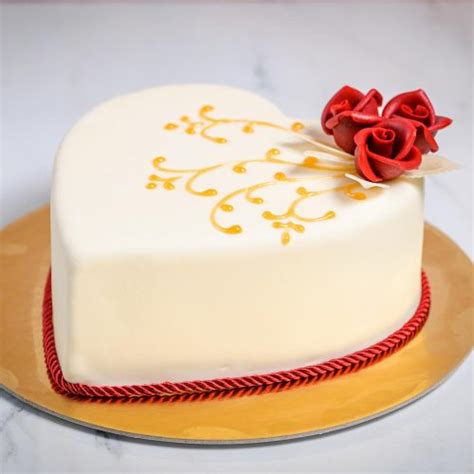 Díszített szív alakú torta tortabevonattal és gyümölcsökkel