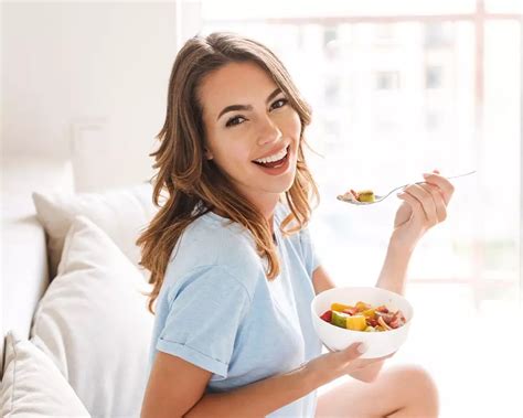 Fiatal nő otthoni környezetben, egészséges ételt fogyasztva