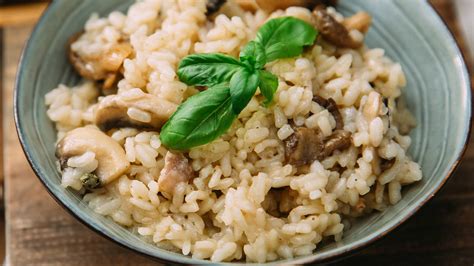 Tálalásra kész csirkés-gombás rizottó, egy pohár borral az asztalon