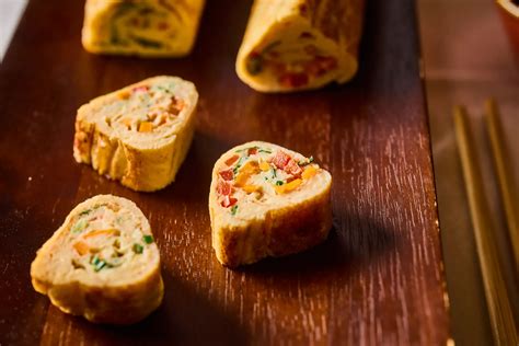 Tamagoyaki tekercs szeletekkel, mellette zöldségek és szójaszósz