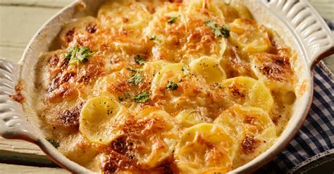 Tejszínes szósz öntése a rétegezett burgonya és zöldségek tetejére