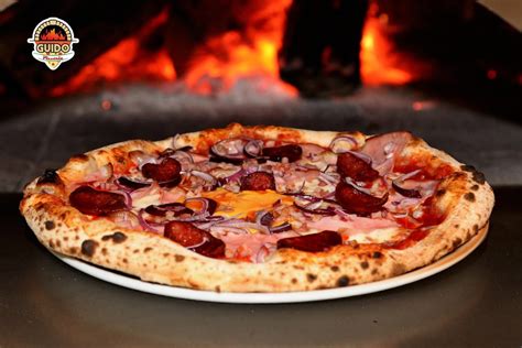 egy frissen sült, gőzölgő nápolyi pizza fatüzelésű kemencében