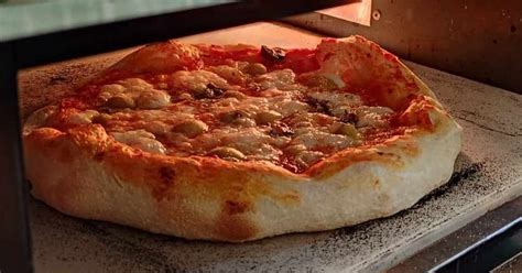 kézműves pizzakészítő, aki a pizzát a kemencébe helyezi
