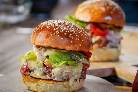 egy ínycsiklandó, rétegezett Dokk hamburger látványos közeli fotója, friss zöldségekkel és olvadt sajttal