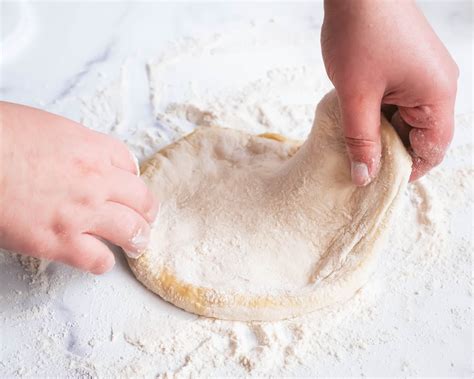 Pizza dough being stretched by hand