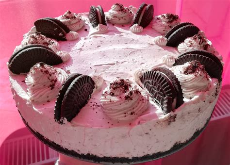 egy díszes Oreo sajttorta, tetején friss eperrel és ehető virágokkal