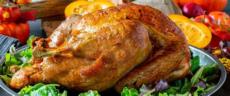 Egy egészben sült, aranybarnára sült pulyka egy tálon, köretekkel és mártással