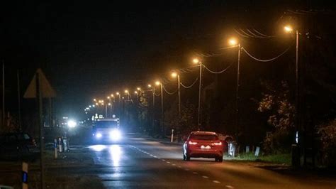 Illusztráció a hiányos infrastruktúráról: egy aszfaltozott út közvilágítás nélkül, szembeállítva egy földúttal, ahol a közvilágítás oszlopai árválkodnak
