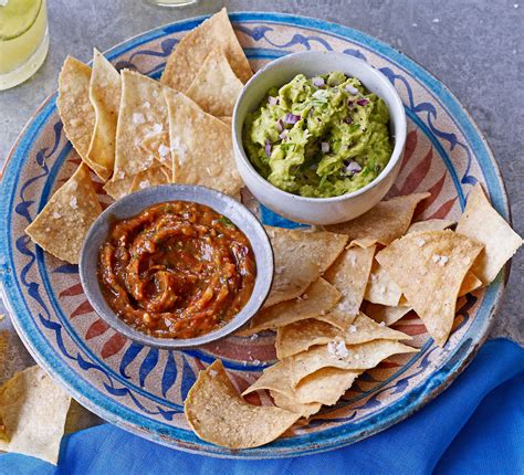 A nachos tál elemei: tortilla chips, friss salsa, reszelt sajt és guacamole egy asztalon