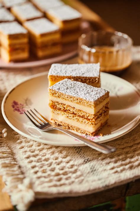 Egy krémes szelet porcukorral meghintve, egy csésze kávé mellett