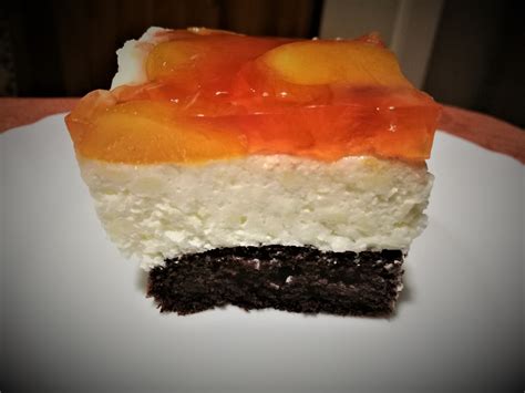 egy szelet barackos totu torta, réteges szerkezetben, friss barackdarabokkal a tetején