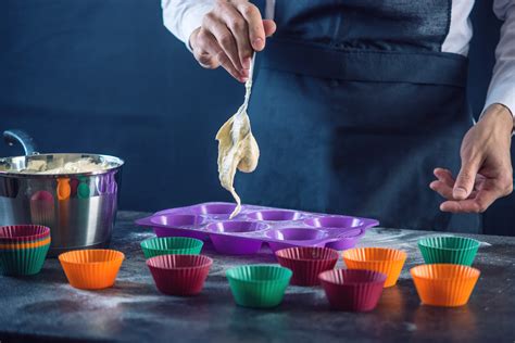 különböző típusú és anyagú muffin sütőformák elrendezve a konyhapulton
