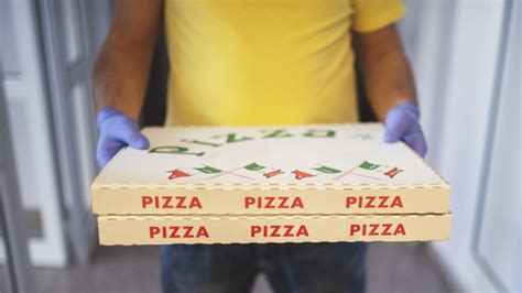 Pizzafutár egy robogón, épp kiszállítást végez