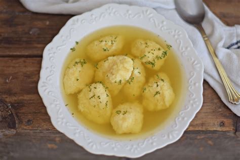 Tálalásra előkészített, gőzölgő szalonnas grízgombóc csirkemellel leves, friss petrezselyemmel díszítve, egy hagyományos magyar tányérban.