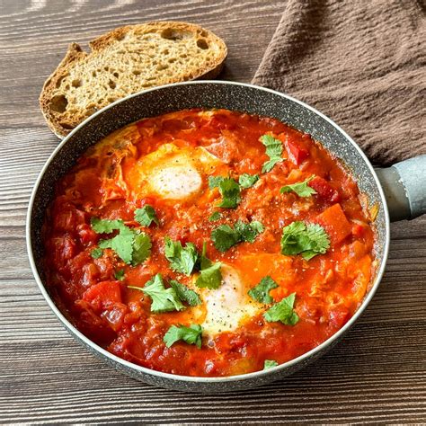 Shakshuka egy serpenyőben, kenyérrel tálalva