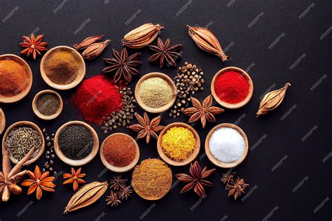 A variety of Indian spices on a wooden table, including turmeric, coriander seeds, cardamom pods, and cumin