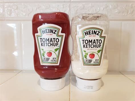 Egy üveg Heinz ketchup egy asztalon, mellette friss paradicsommal megrakott szendvicsek