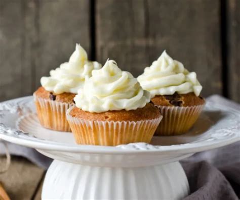 Frissen sült gluténmentes sárgarépás cupcake-ek krémsajtos díszítéssel egy rusztikus faasztalon