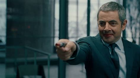 Johnny English portréja öltönyben, kémfelszereléssel a háttérben