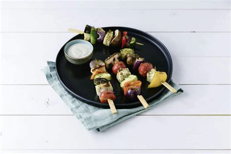 Különböző mártogatóssal tálalt sült zöldségnyársak