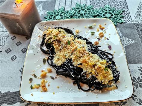 Tányérra halmozott fekete spagetti parmezánnal megszórva