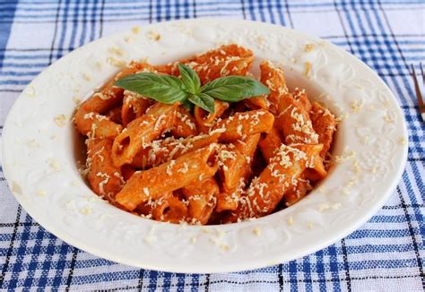 Tálalt paradicsomos penne sült csirkemell darabokkal és friss bazsalikommal