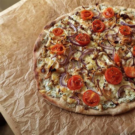 Különböző pizzák egy fatáblán, kiemelve a körtés pizzát