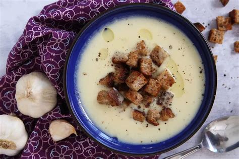 Hagymakrémleves tálalva, a tetején egy kanál natúr joghurttal és pirított kenyérkockákkal