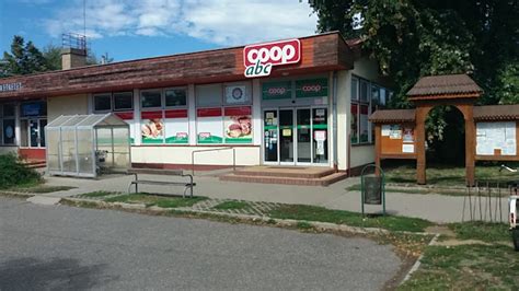 Coop üzlet homlokzata napfényben, mosolygós vásárlókkal