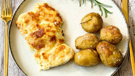 Fotó egy tepsiben sült, aranybarnára sült tejfölös csirkecombról, mellette sült burgonyával.