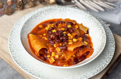 egy tál gőzölgő chilis bab, gazdagon megszórva kukoricával és friss fűszerekkel