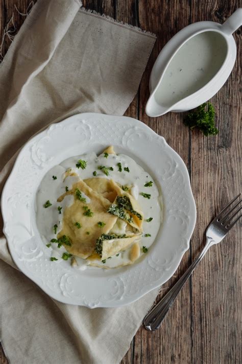 Spenótos-ricottás ravioli egy tányéron, sajtmártással leöntve