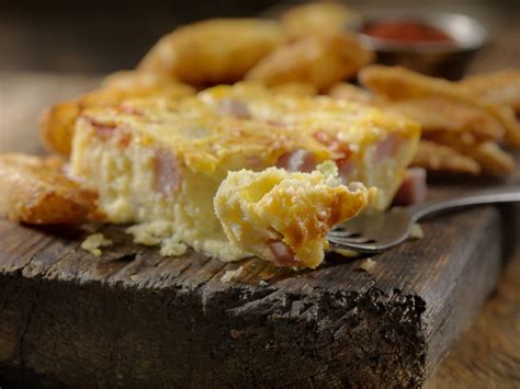 szeletelt, gazdag töltelékű tepsis omlett, amelyen látszanak a gomba és szalonna darabok