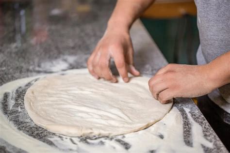 Kézzel gyúrt pizzatészta egy lisztezett deszkán
